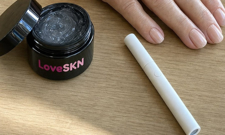 The LoveSKN jelly glue jar and the white UV wand on a wooden table