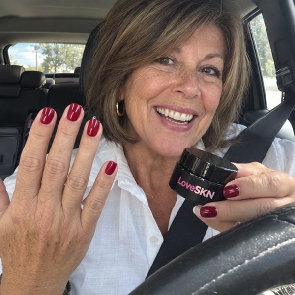 Customer in her car showing cherry red press-on nails and the LoveSKN jar